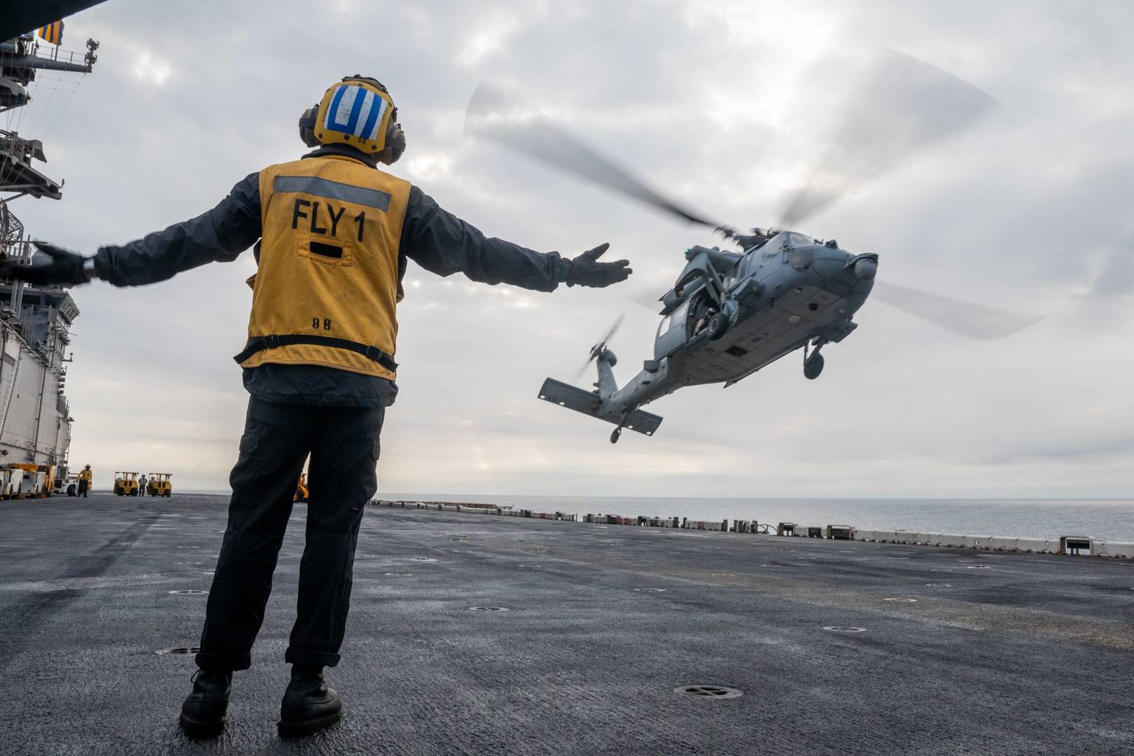 Американский военнослужащий обеспечивает посадку вертолета на палубу авианесущего корабля