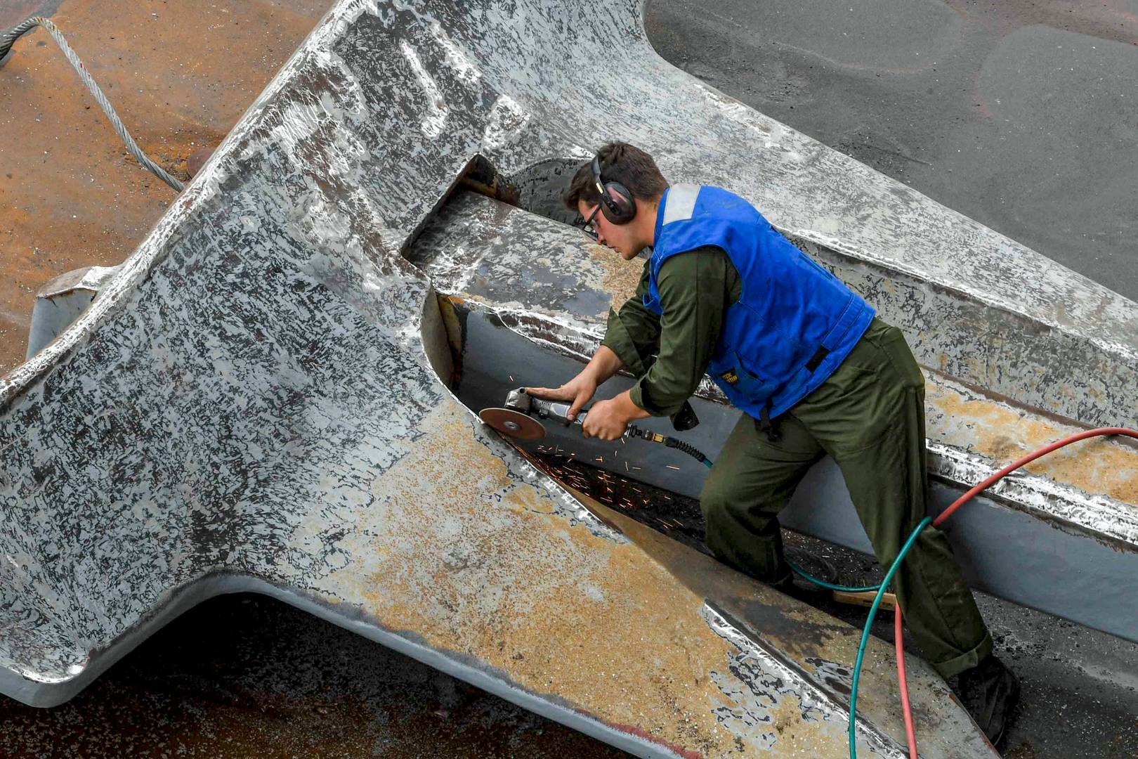 Рабочий военной верфи полирует якорь экспедиционной морской базы Hershel «Woody» Williams ВМС НАТО