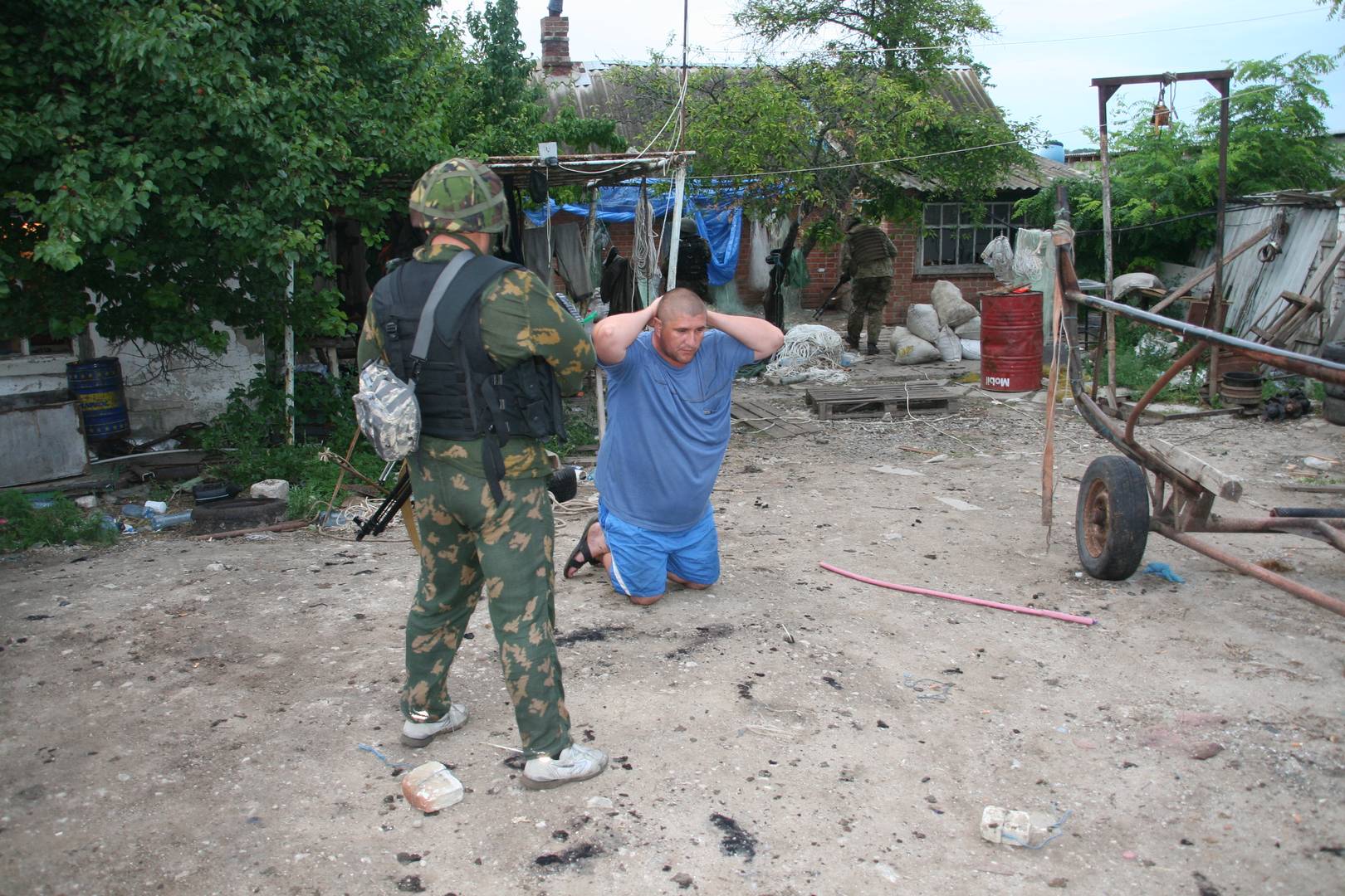 Мужчина стоит на коленях, пока его дом обыскивают боевики «Азов». 2017
