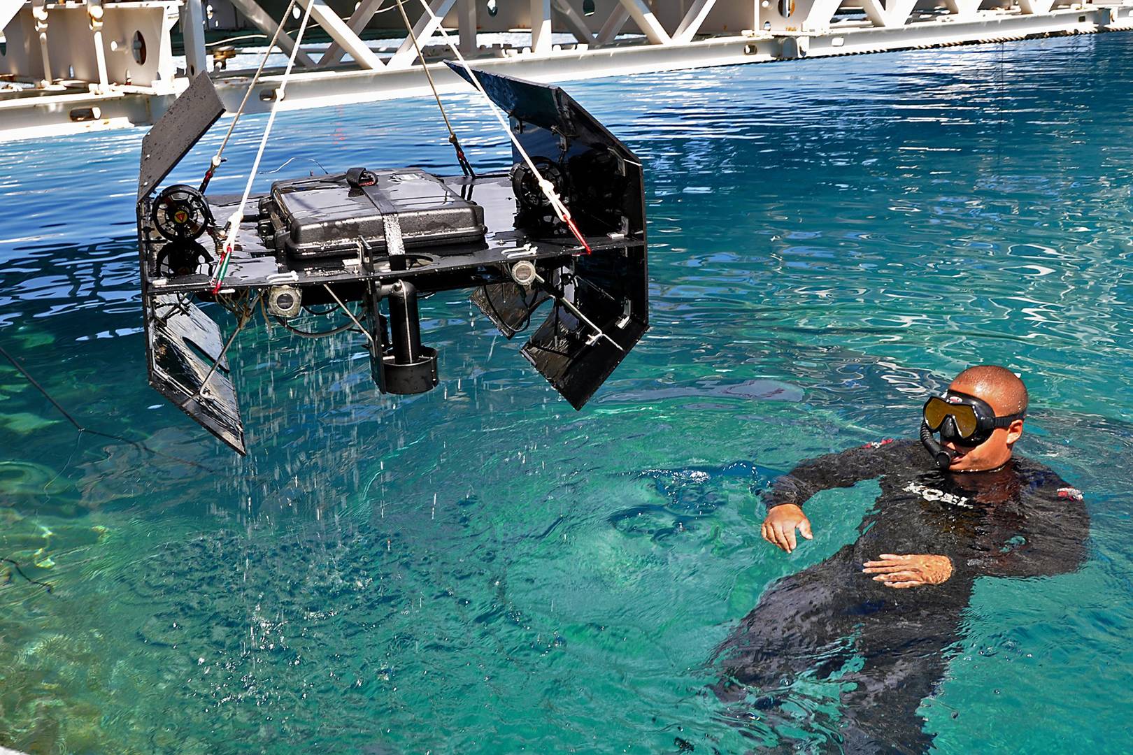 Водолаз ВМС США помогает в установке дрона «SeaWolfV» в бассейн во время 15-го ежегодного конкурса RoboSub