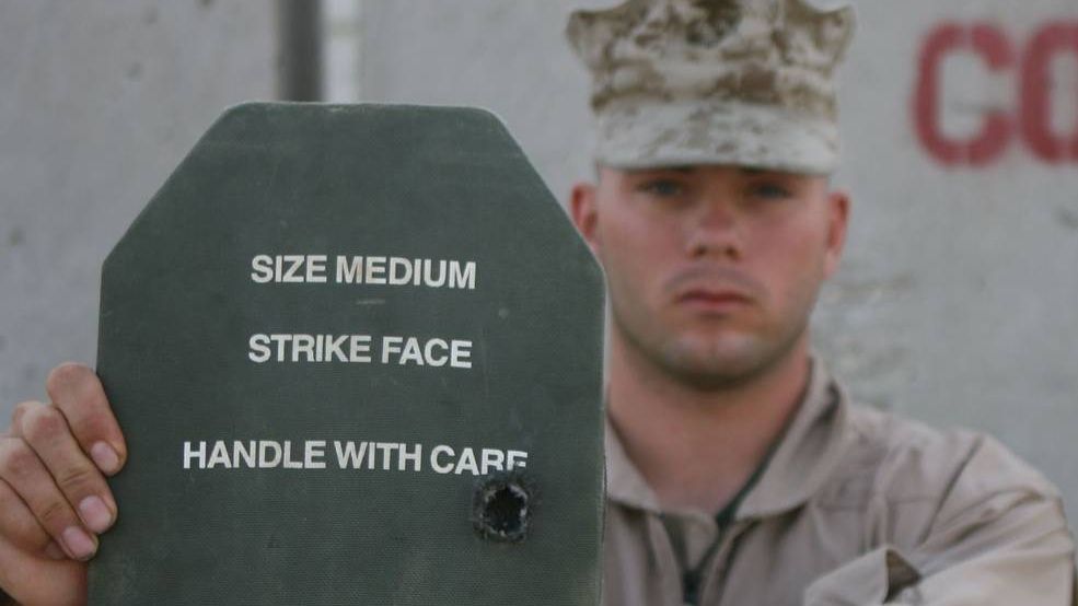 Военнослужащий США показывает пластину бронежилета со следами попадания пули
