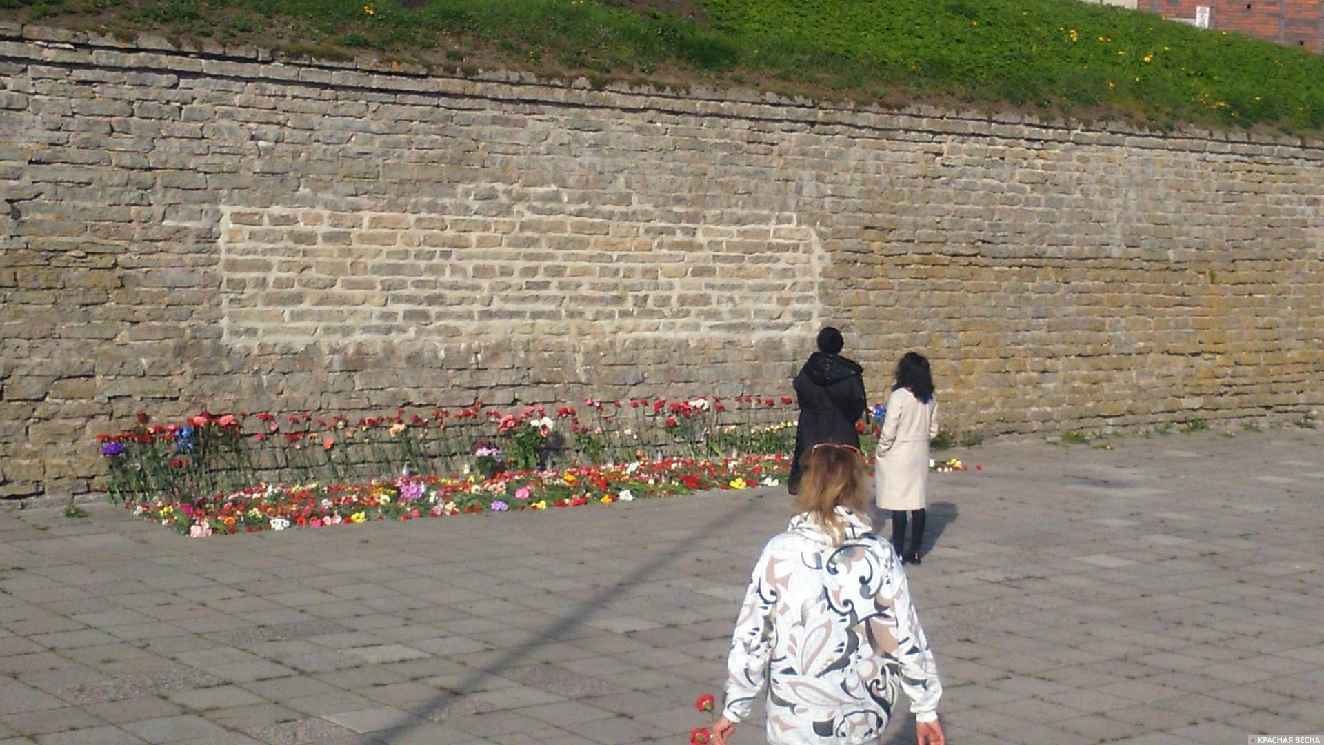 Жители Нарвы возлагают цветы на место снесенных мемориальных плит. 9 мая 2023