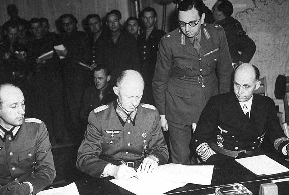 Генерал-полковник А. Йодль (в центре) подписывает капитуляцию Германии в Реймсе