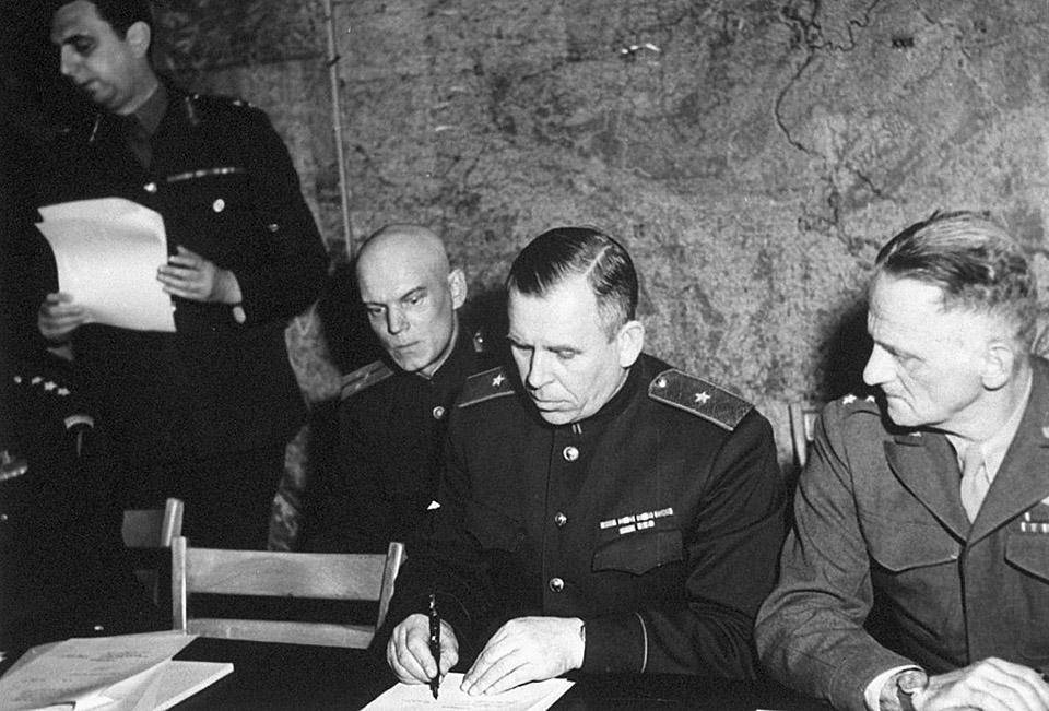 И. Суслопаров подписывает договор о капитуляции Германии в Реймсе. Справа — американский генерал К. Спаатц