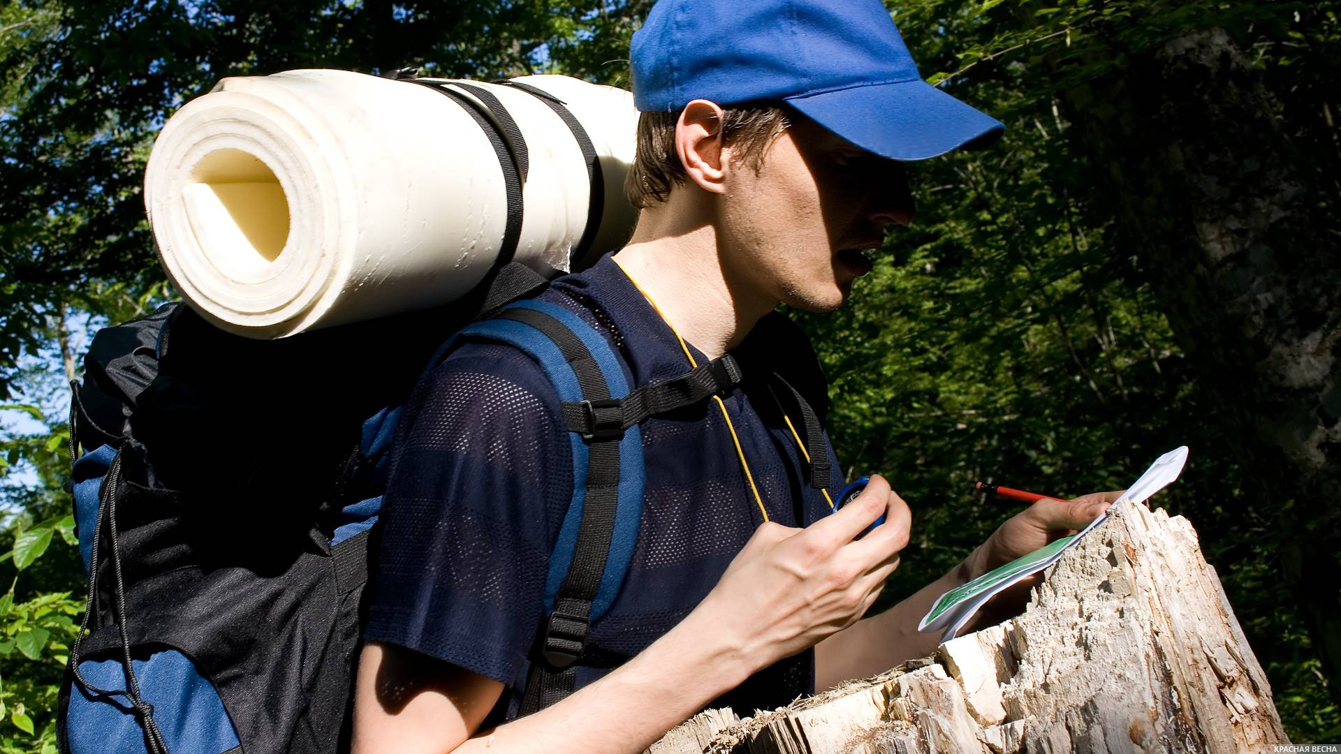 Турист с рюкзаком сверяется по компасу и карте