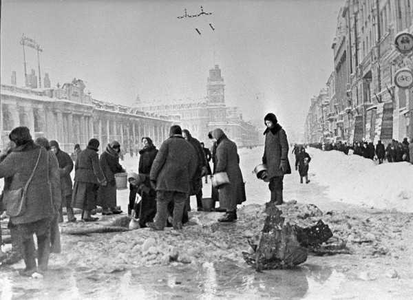 Жители блокадного Ленинграда набирают воду в пробоинах, в асфальте, на Невском проспекте. 1941 г.