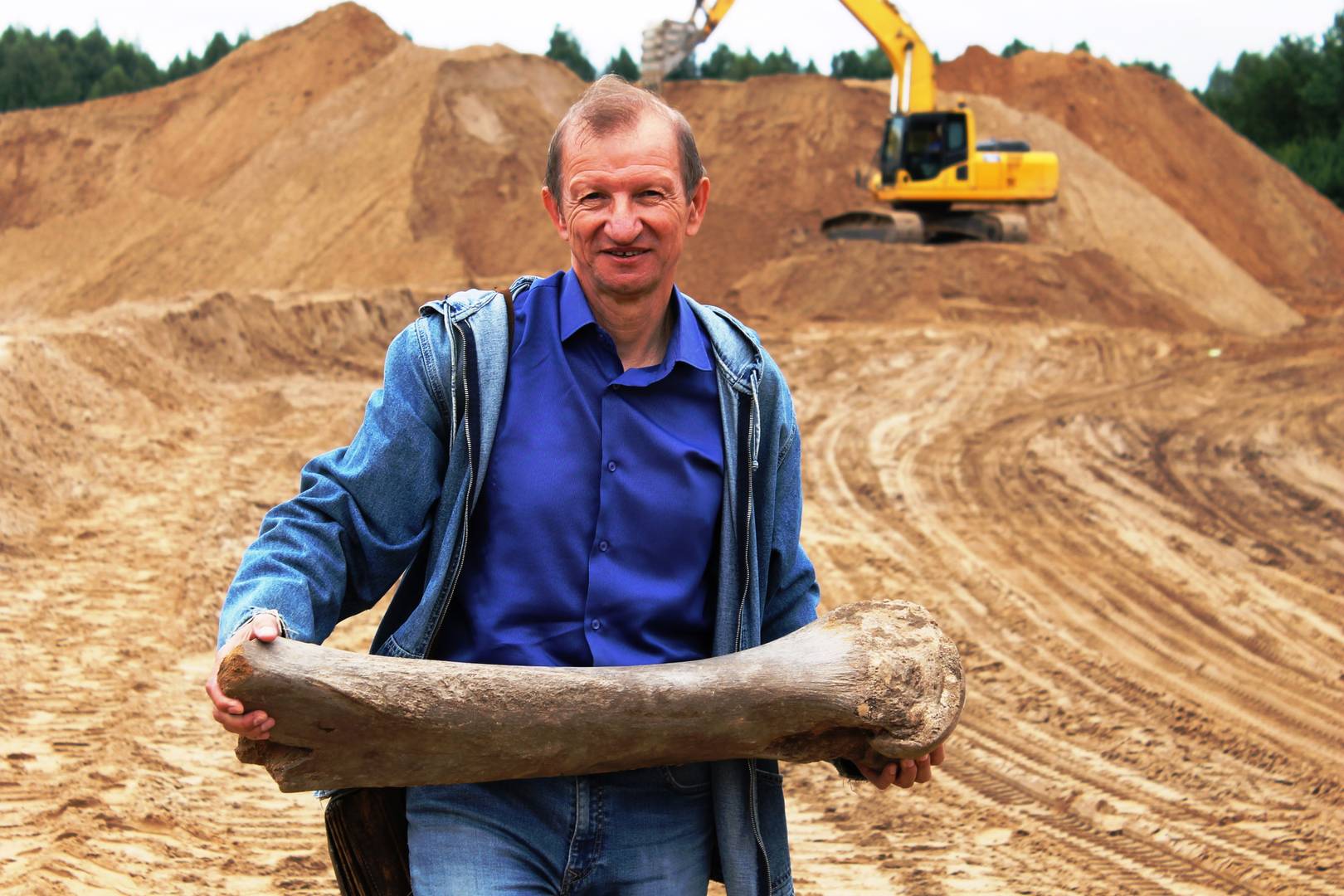 Геолог Валерий Чернышов с найденной костью мамонта.