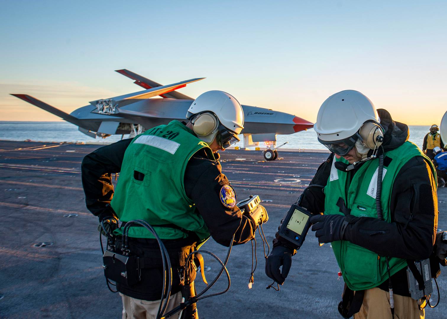 Операторы дрона MQ-25 Stingray изучают устройство дистанционного управления фирмы SECO на палубе авианосца