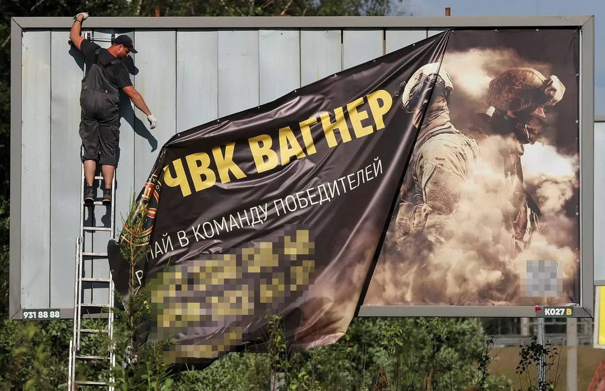 Рабочий снимает баннер, рекламирующий службу в частной наемной группе «Вагнер», на окраине Санкт-Петербурга