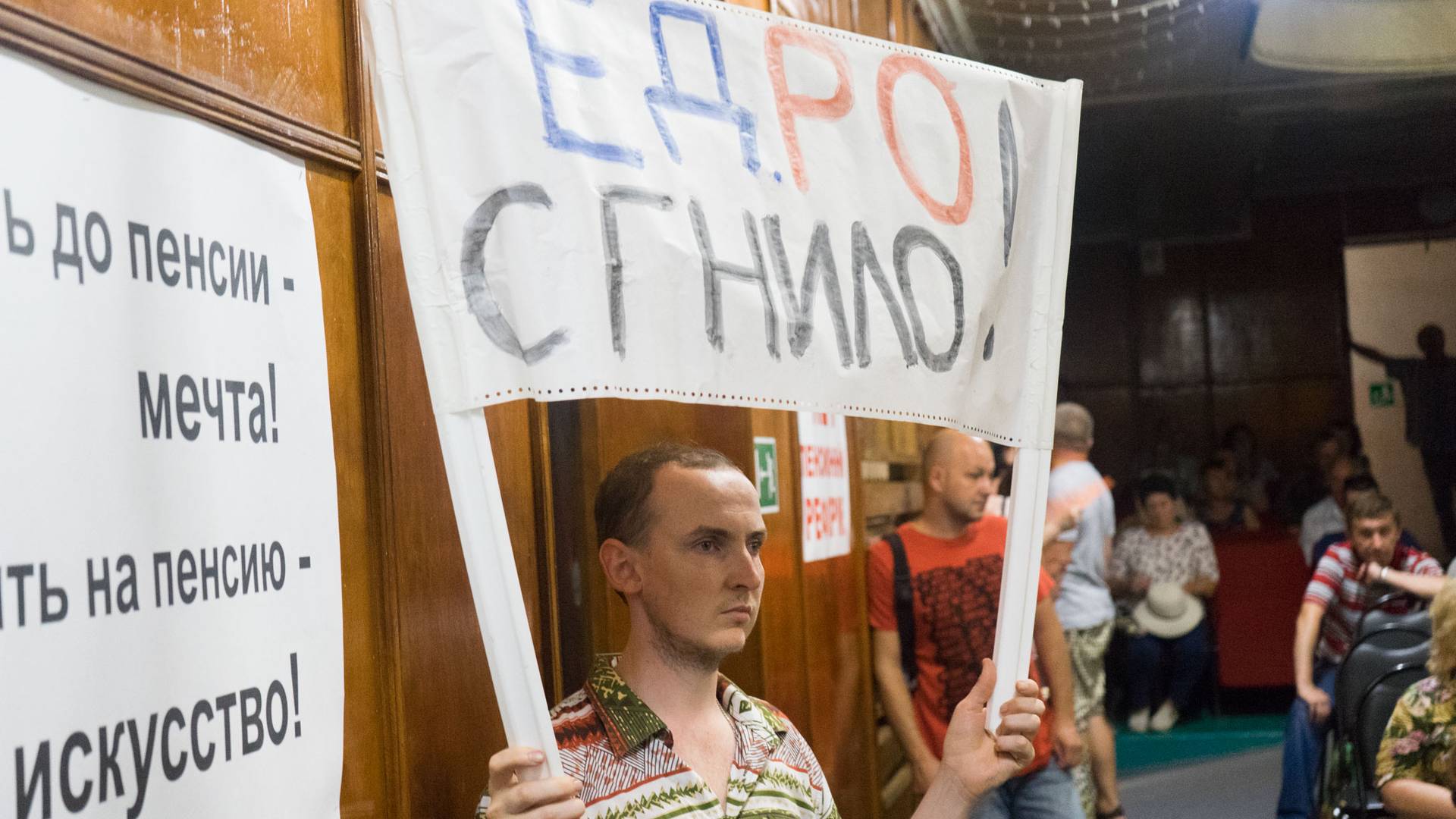 Активист держит плакат «ЕДРО Сгнило!» на собрании КПРФ против пенсионной реформы