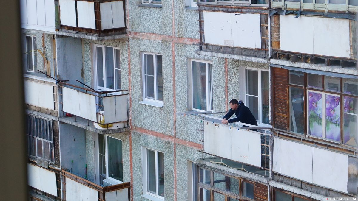 Мужчина дышит воздухом на балконе в период режима самоизоляции