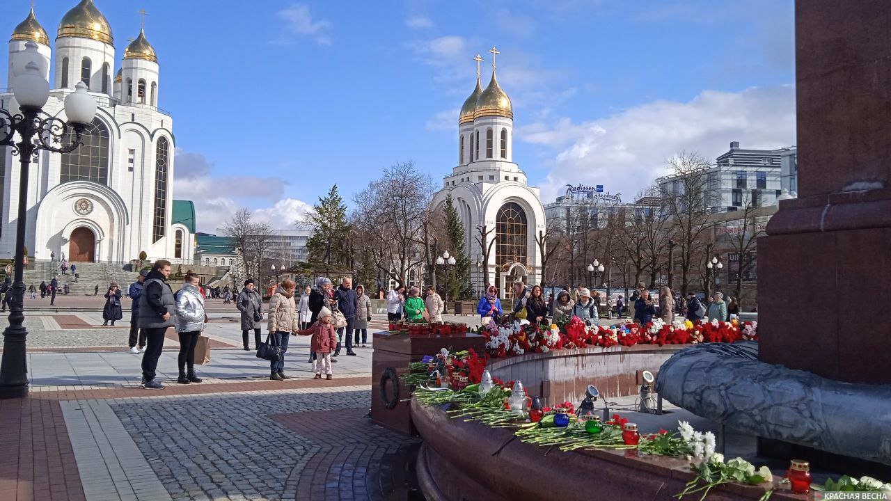 Местные жители приносят цветы и свечи к стихийному мемориалу на площади Победы в Калининграде в память жертв теракта, произошедшего в подмосковном центре «Крокус Сити Холл»