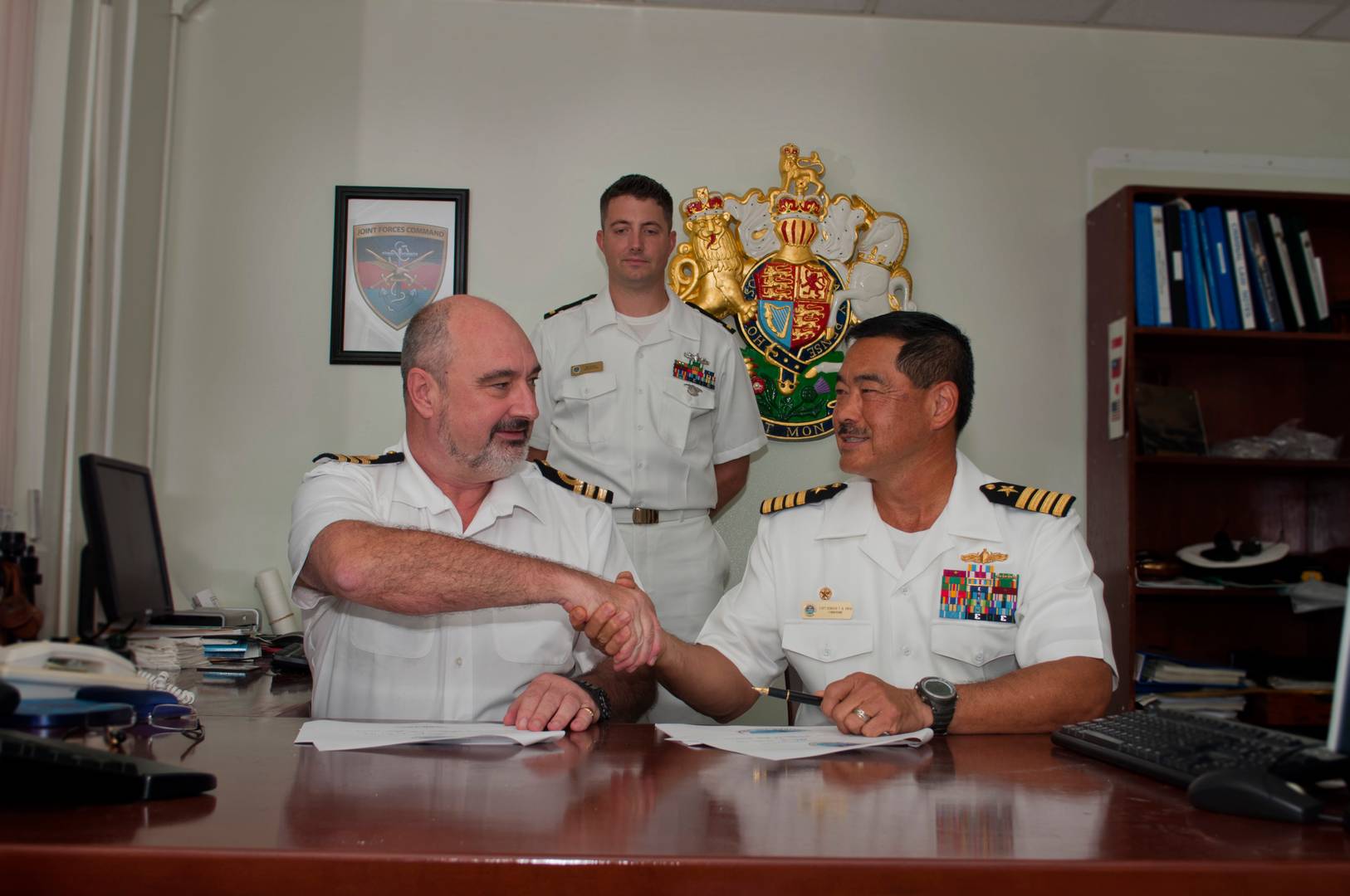 Представитель ВМС Великобритании на базе Диего-Гарсия жмет руку американскому морскому офицеру после подписания соглашения о совместном владении островами Чагос