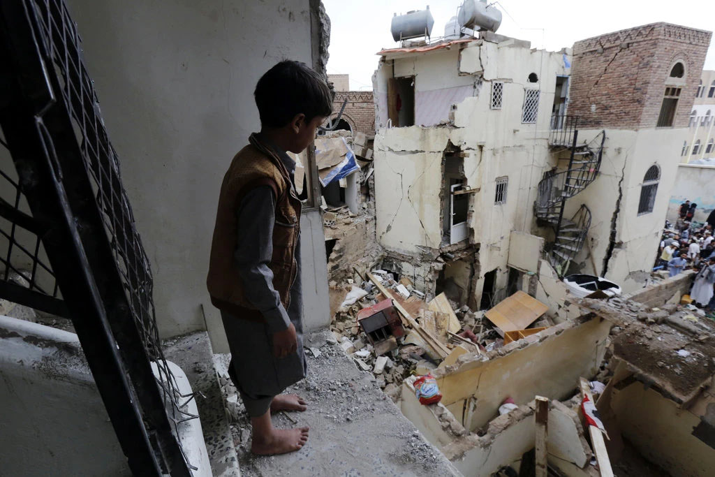 Ребенок смотрит на разрушенную столицу Йемена
