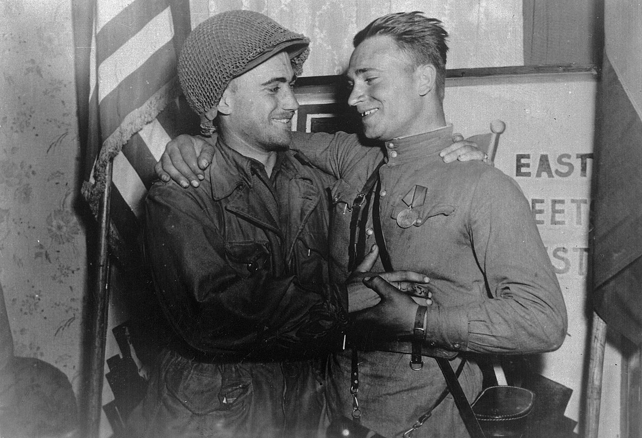 Лейтенант У. Робертсон и лейтенант А. С. Сильвашко на фоне надписи «Восток встречается с Западом». Встреча на Эльбе