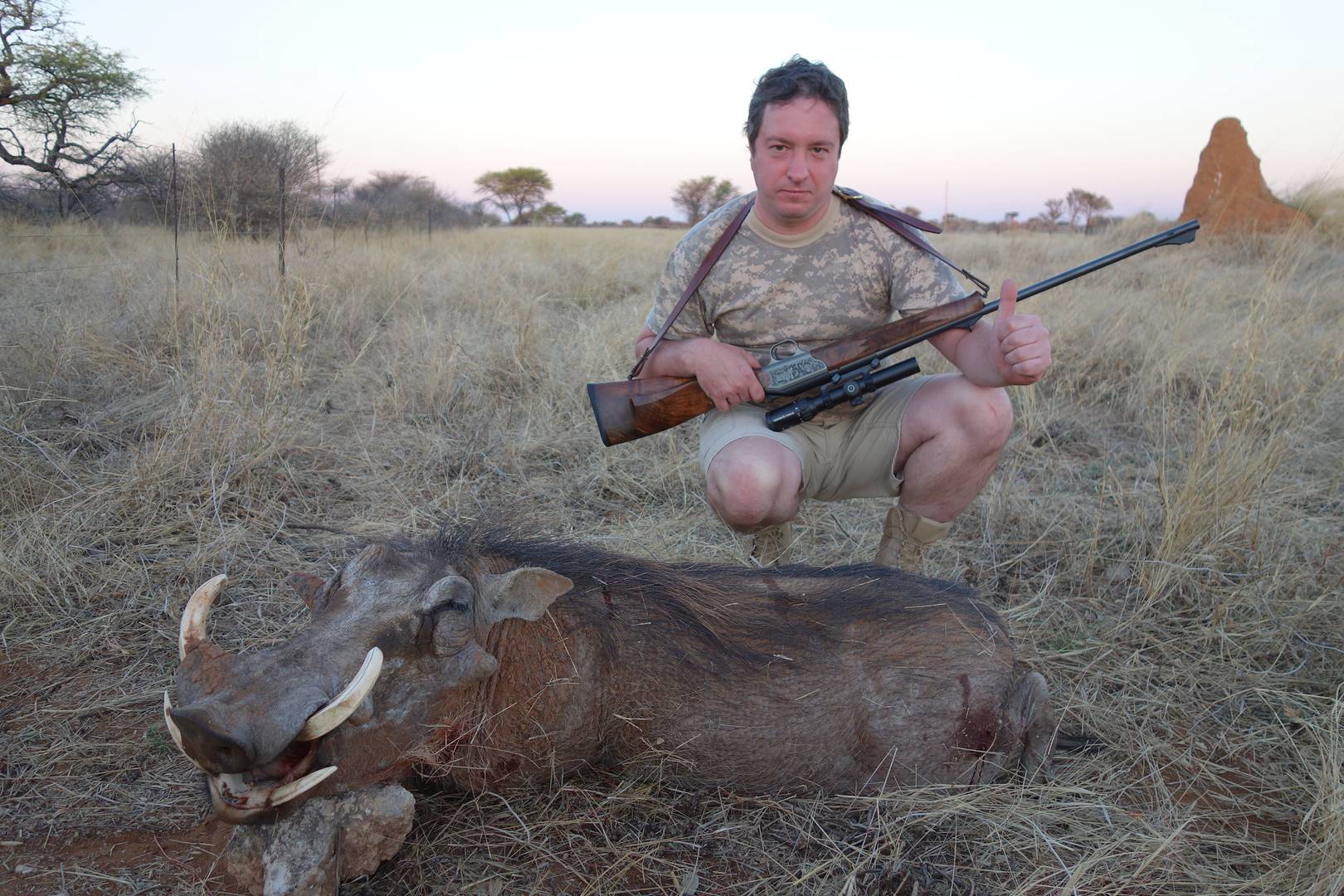 Охотник с трофеем бородавочника в Намибии