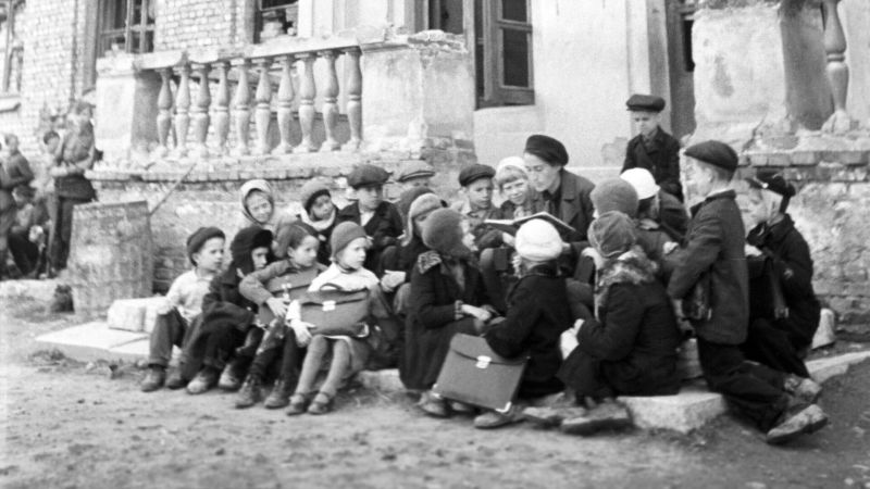 Урок на крыльце разрушенной немецкими обстрелами школы в блокадном Ленинграде. 1943