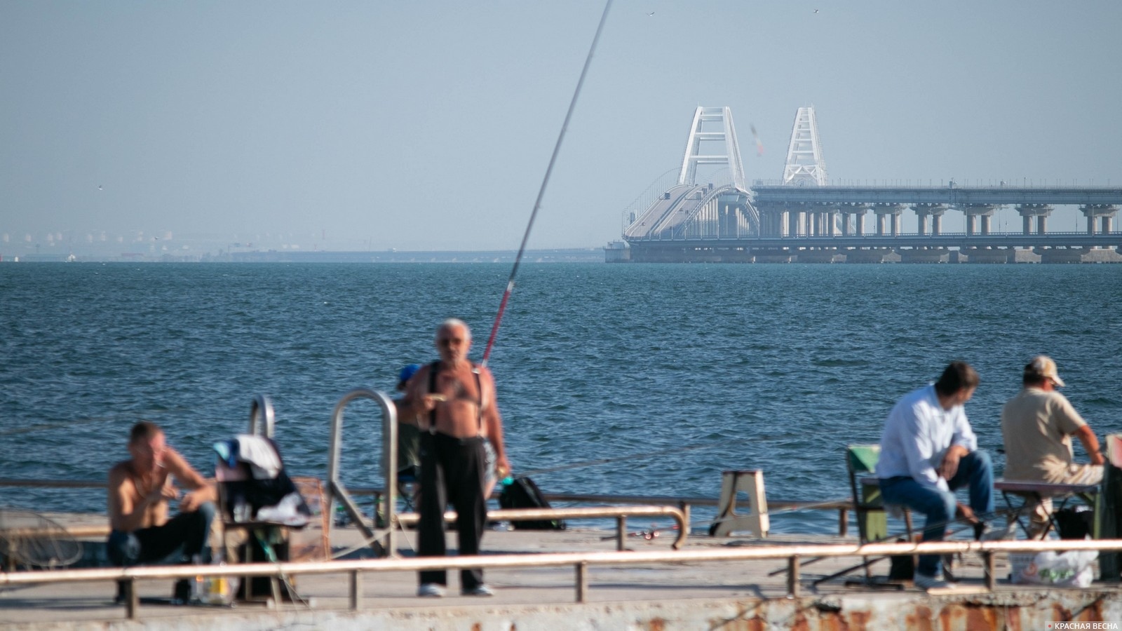 Рыбаки на причале на фоне Крымского моста. Керчь, Крым