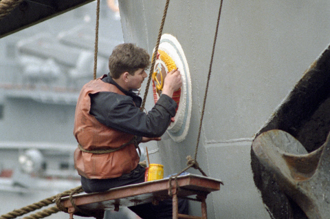 Матрос обновляет красками герб СССР на корме корабля Черноморского флота. 1992