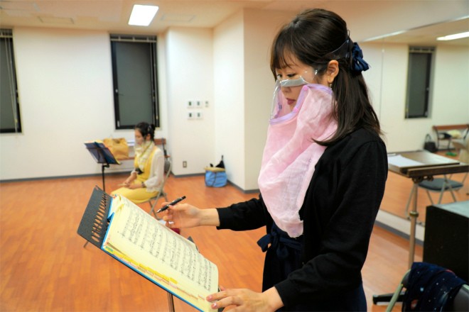 Женщина в маске для певцов берет урок в школе Nagoya Nikikai