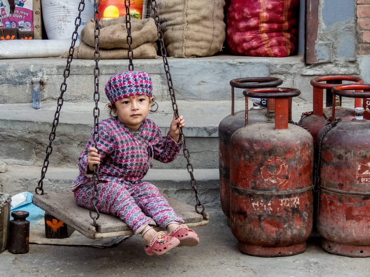 Ребенок качается на качели возле газовых баллонов