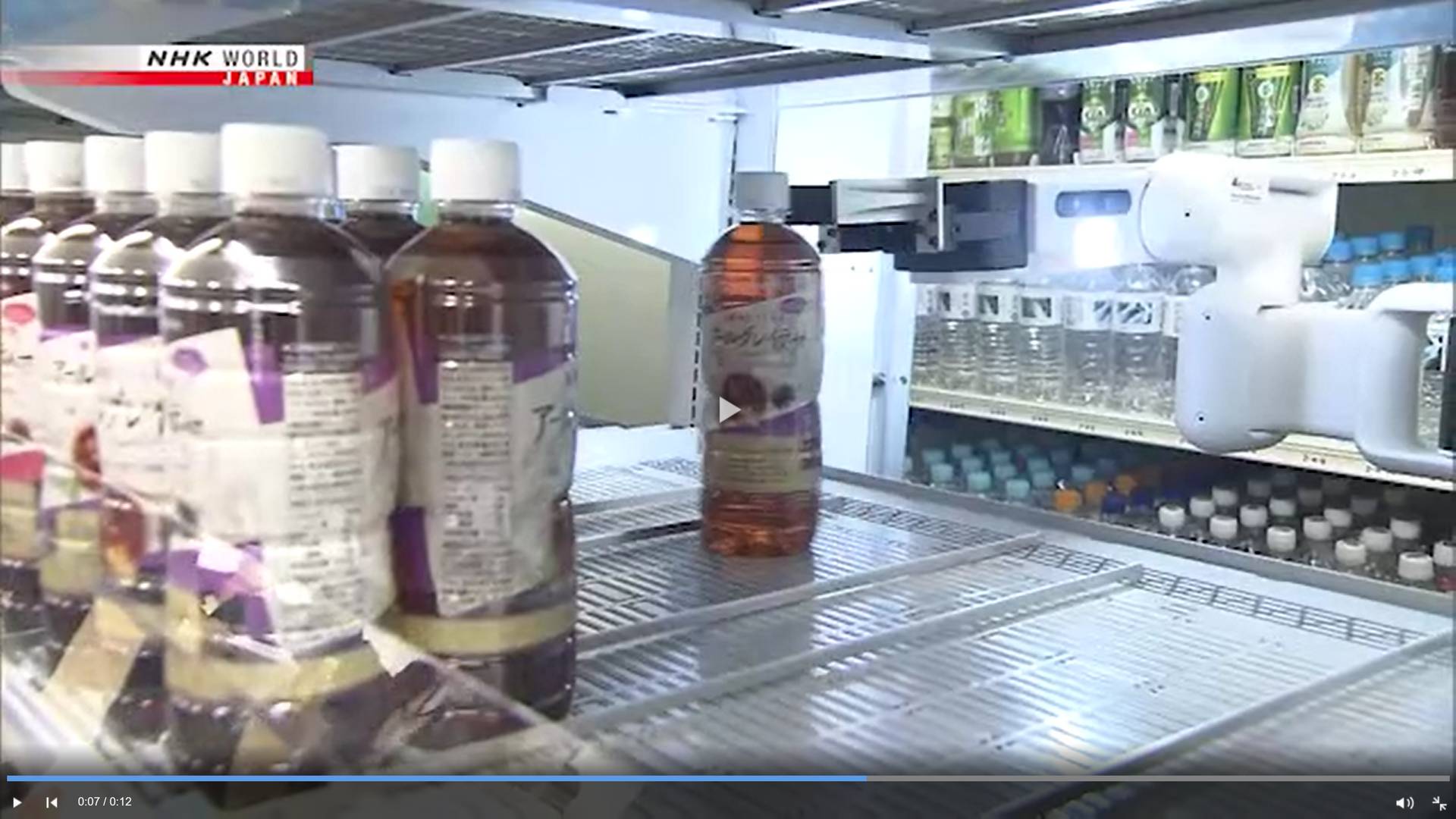 Робот опускает бутылку на полку — цитата из видео «Convenience store chain deploys first shelf-stocking robot» телеканала NHK