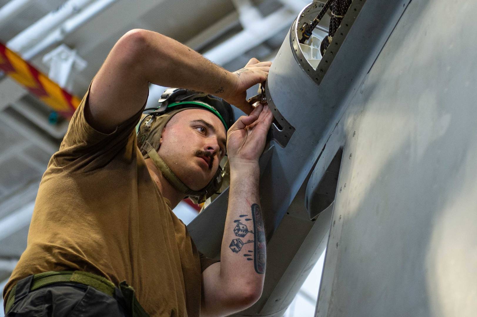 Авиамеханик ВМС США ремонтирует самолет на ангарной палубе авианосца Carl Vinson
