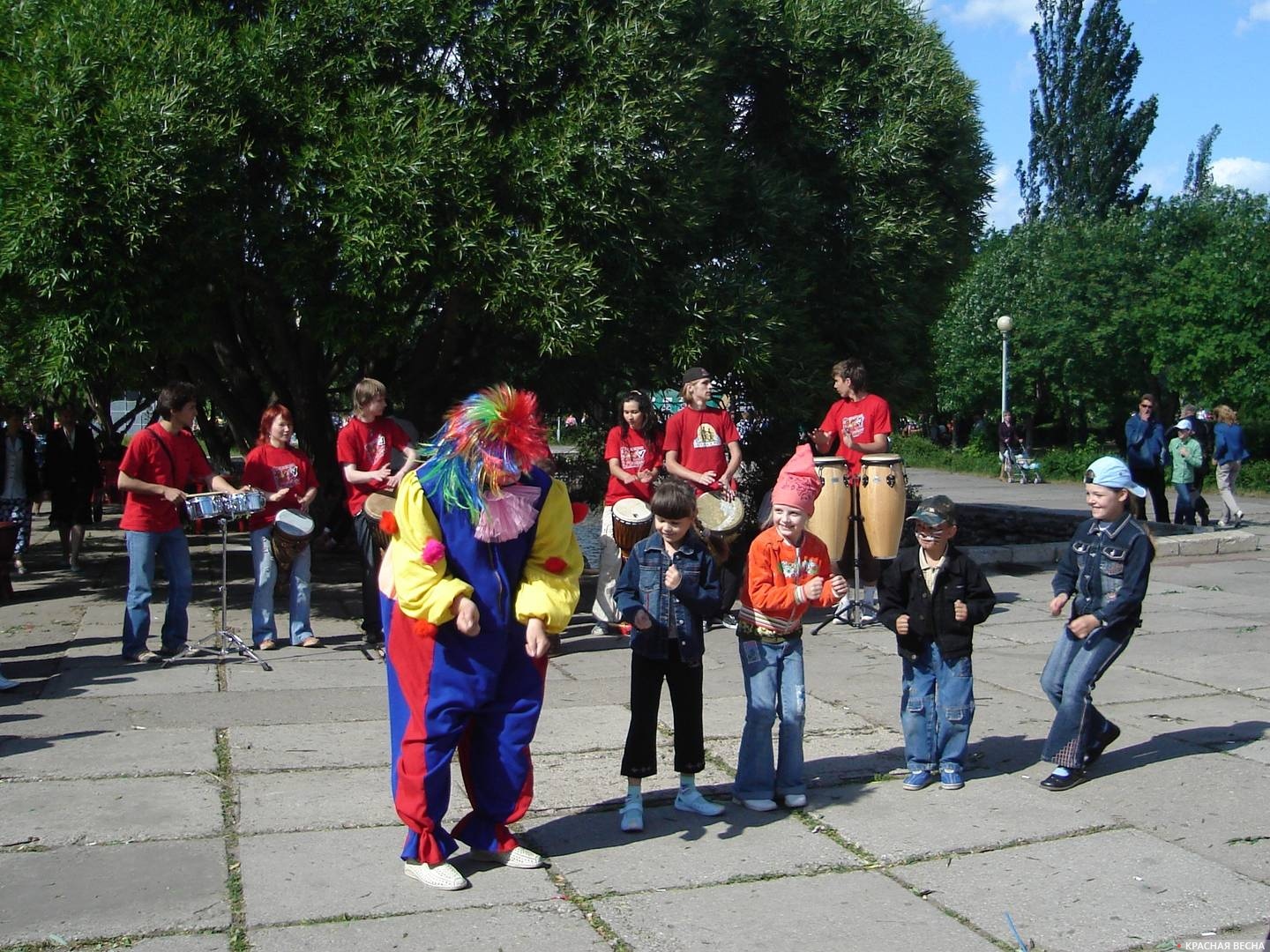 Клоун и дети танцуют под звуки этнических барабанов
