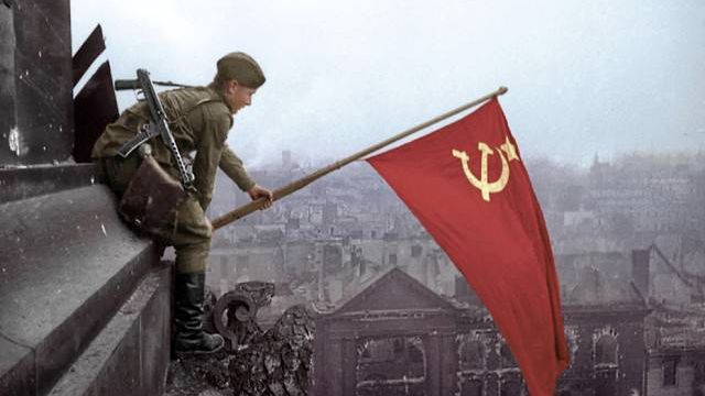 Боец Красной Армии водружает знамя на одном из зданий. Берлин 1945 год