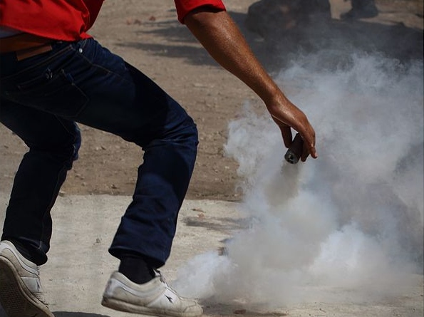 Палестинский демонстрант кидает гранату со слезоточивым газом