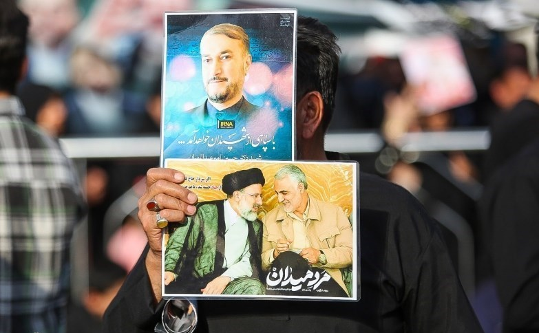 Мужчина с портретами Раиси и Абдоллахияна, погибших в результате крушения вертолета, на церемонии похорон