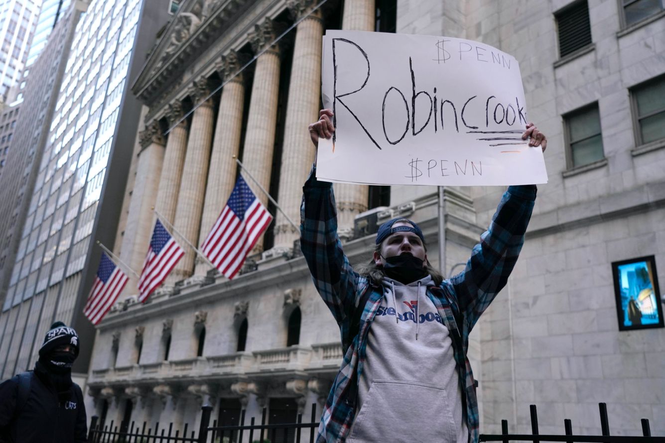 Протестующий перед зданием Уолл-стрит с плакатом «Robincrook» («Робин-мошенник»). 28 января 2021 года