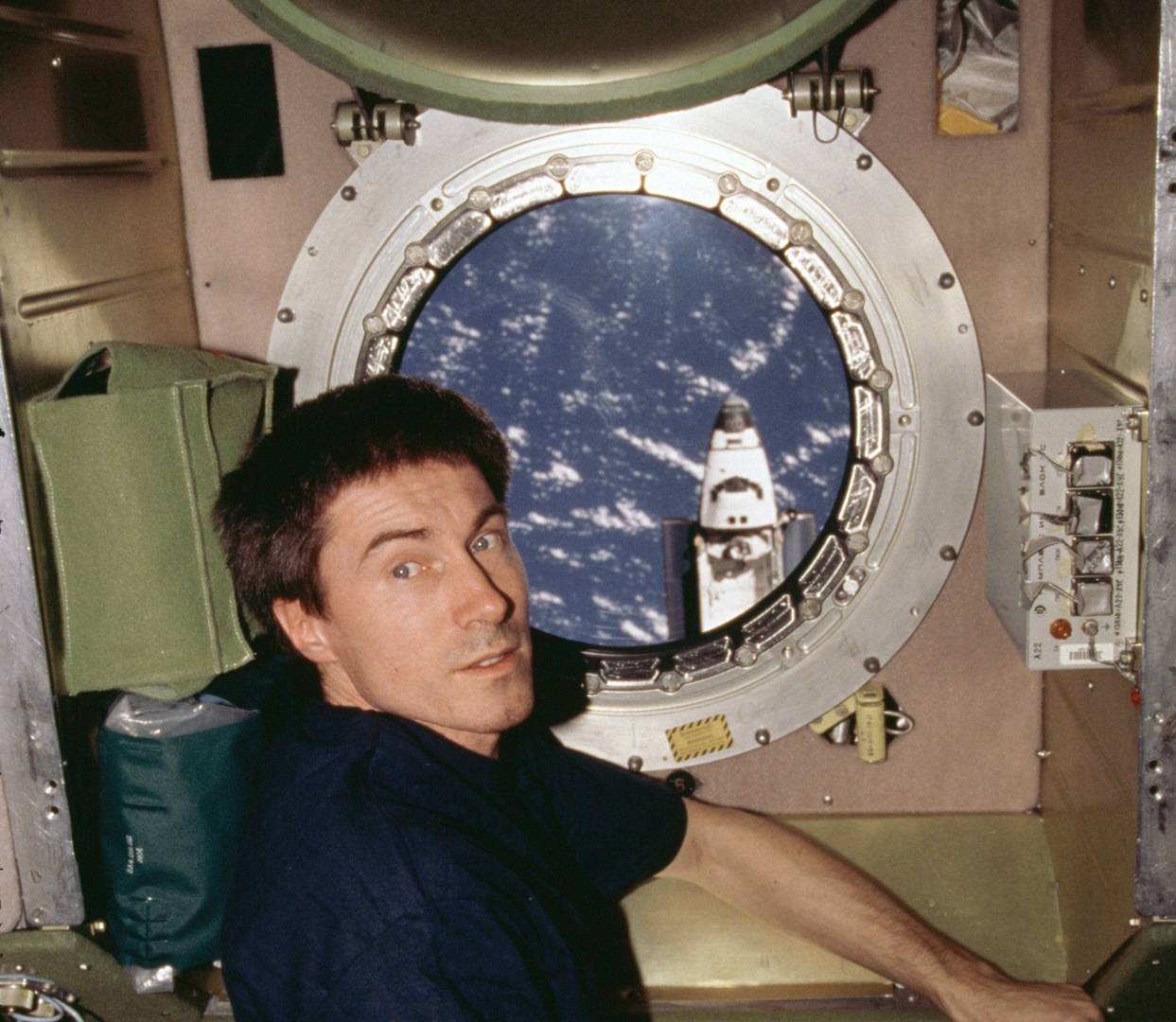 Сергей Крикалёв на фоне иллюминатора модуля «Звезда» на МКС