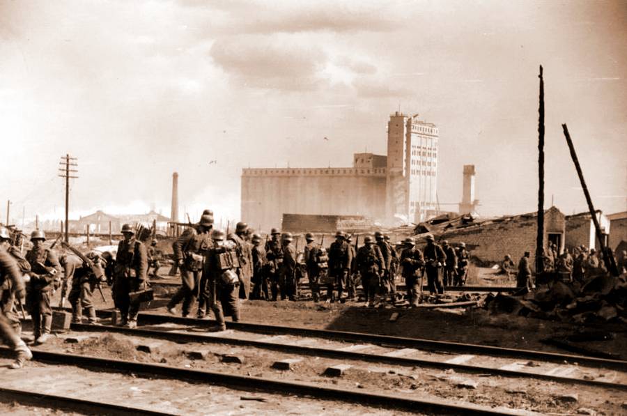 Солдаты 94-й пехотной дивизии вермахта на фоне элеватора. Так как фасад здания еще не сильно разрушен, снимок сделан не позднее 18 сентября 1942 года