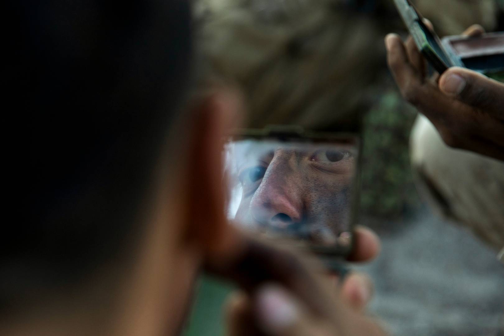 Морской пехотинец США наносит камуфляжную краску, чтобы скрыться от воздушного наблюдения условного противника