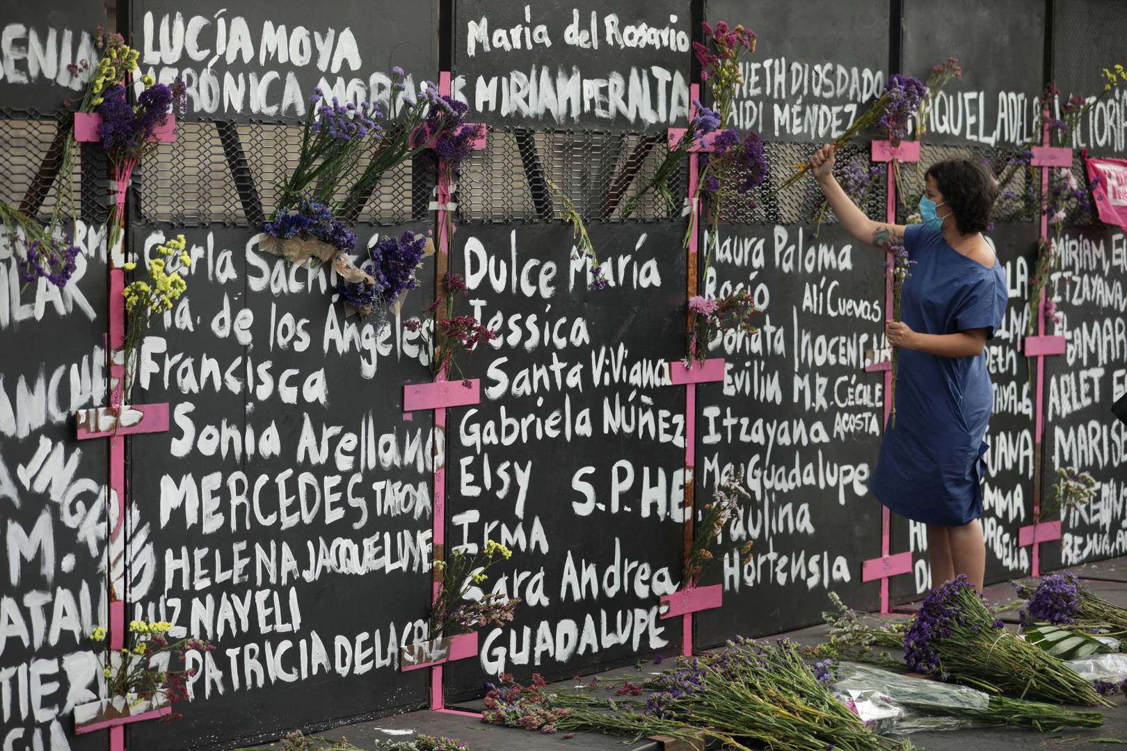 Мексиканки, возлагающие цветы к стене, ограждающей президентский дворец в Мехико