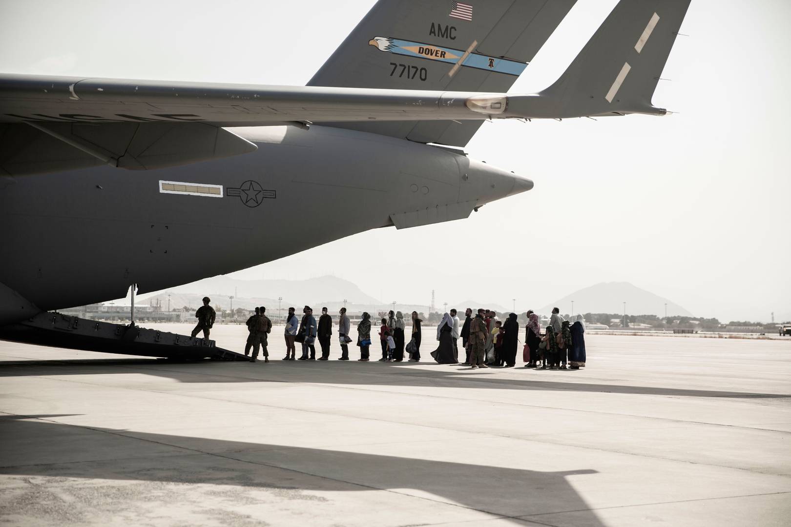 Афганские беженцы ожидают посадки в военно-транспортный самолет Boeing C-17 Globemaster III во время эвакуации из Международного аэропорта имени Хамида Карзая