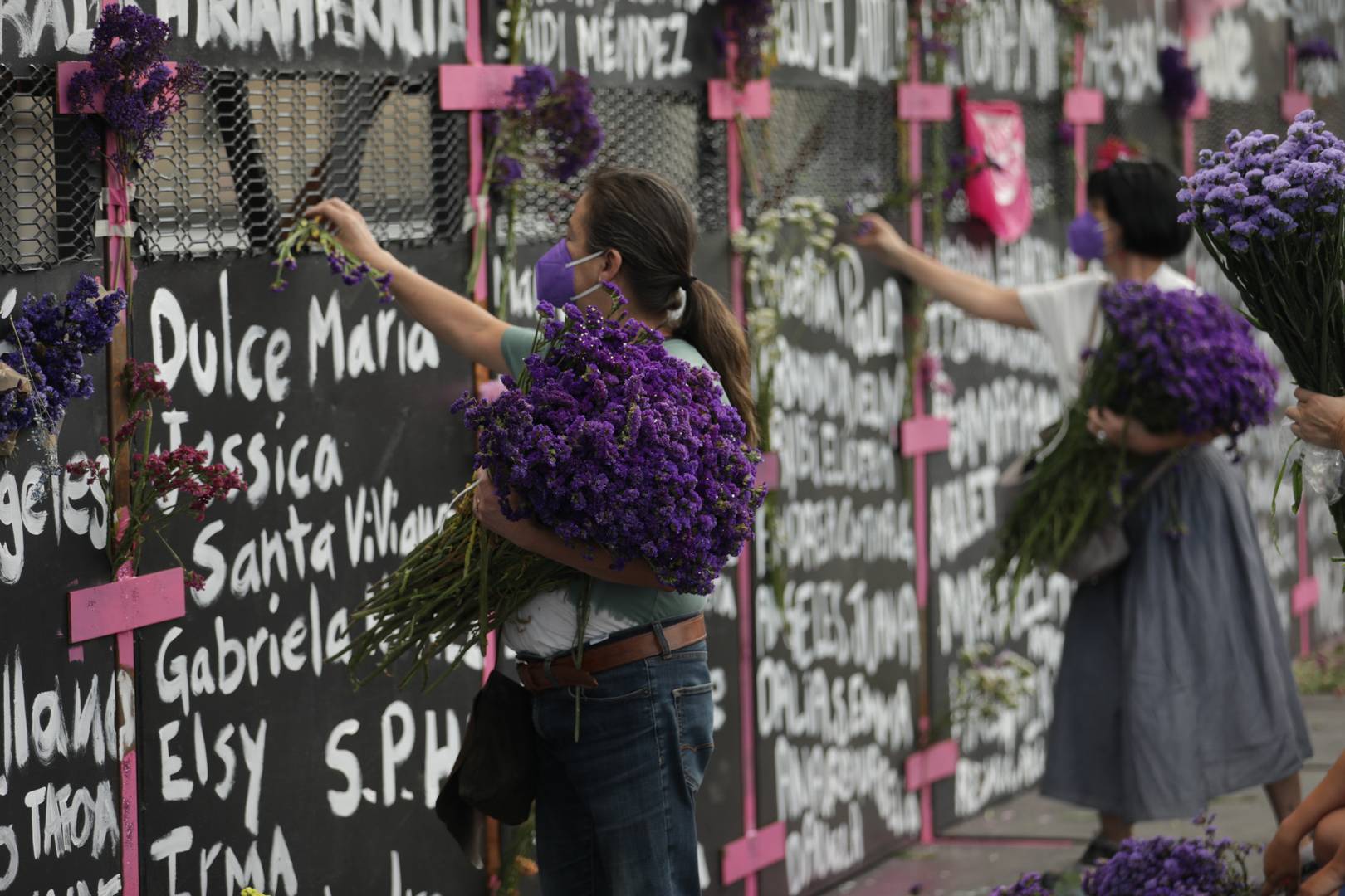 Мексиканки, возлагающие цветы к стене, ограждающей президентский дворец в Мехико