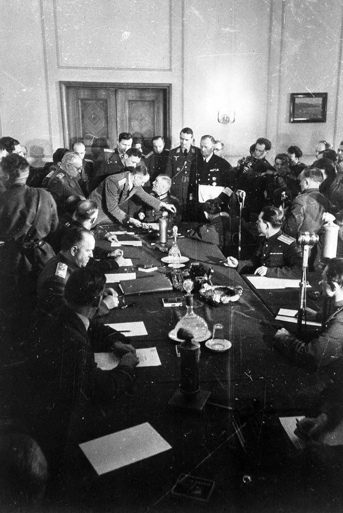 Немецкому фельдмаршалу Кейтелю, подписывающему Акт о безоговорочной капитуляции Германии в Карлсхорсте, подают текст Акта. Слева за столом сидит маршал Жуков