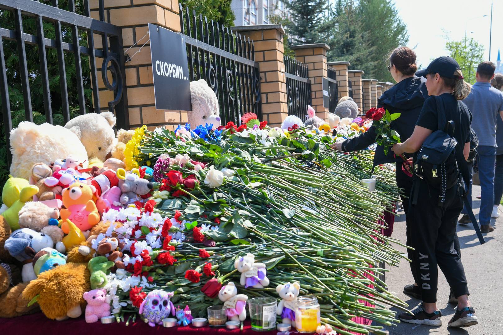 Люди несут цветы и игрушки в мемориалу у лицея, где произошла трагедия